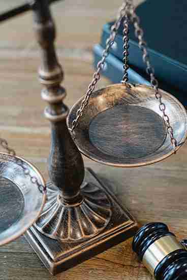 A courthouse weight scale with a black wooden gavel and documents in the background